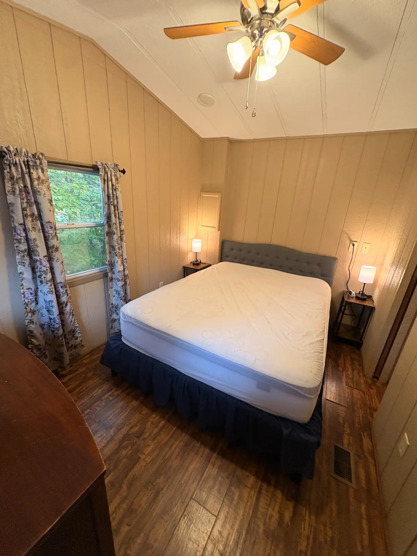 East Oak Lane 6 — Bedroom with a queen bed, tufted grey headboard, matching nightstands with lamps and a sloped ceiling fan