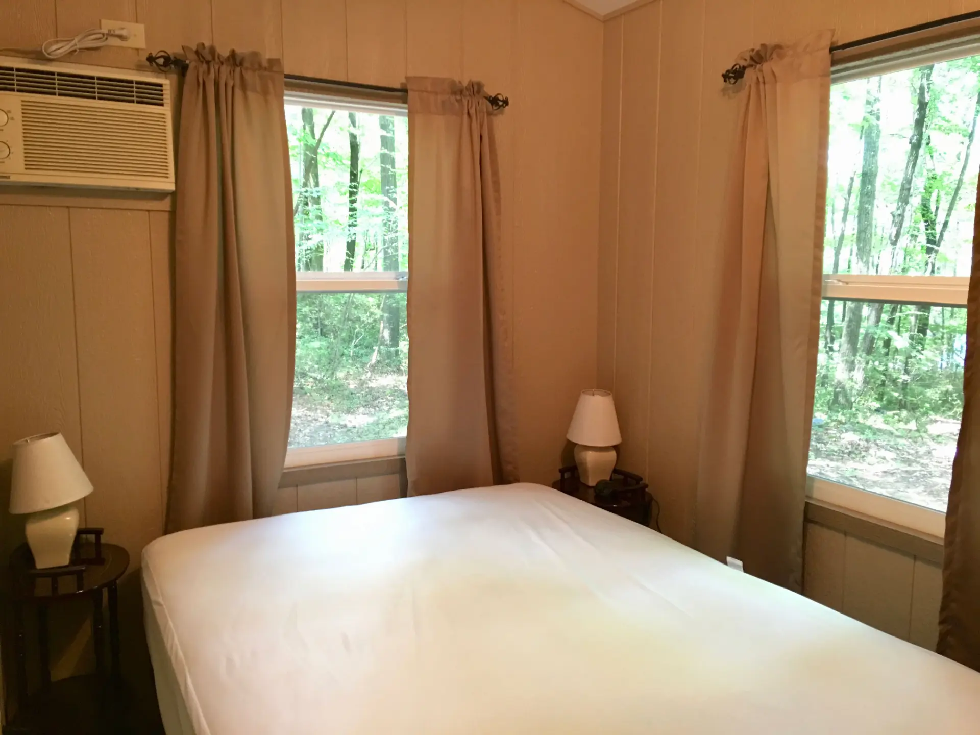 West Oak Lane 9 — Main bedroom with a double bed, nightstand lamps and windows looking into the trees