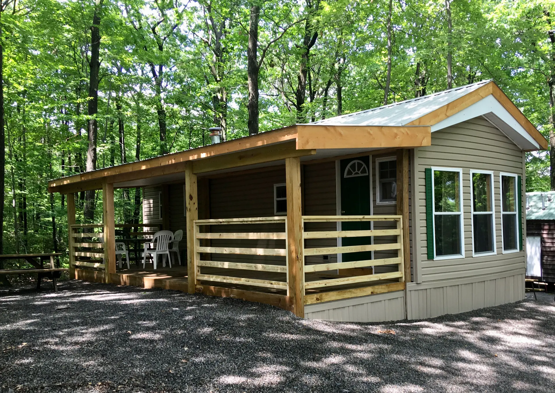 Cabin with a covered wooden porch surrounded by green forest