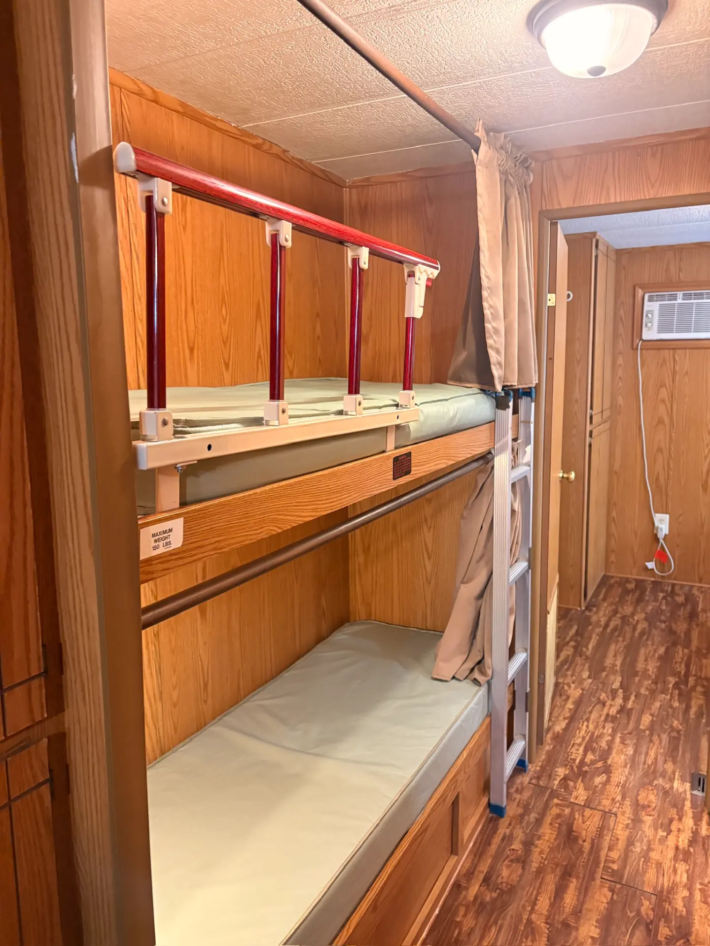 West Oak Lane 10 — Bunk room with wooden bunk beds, privacy curtains, a ladder and a view toward the hallway
