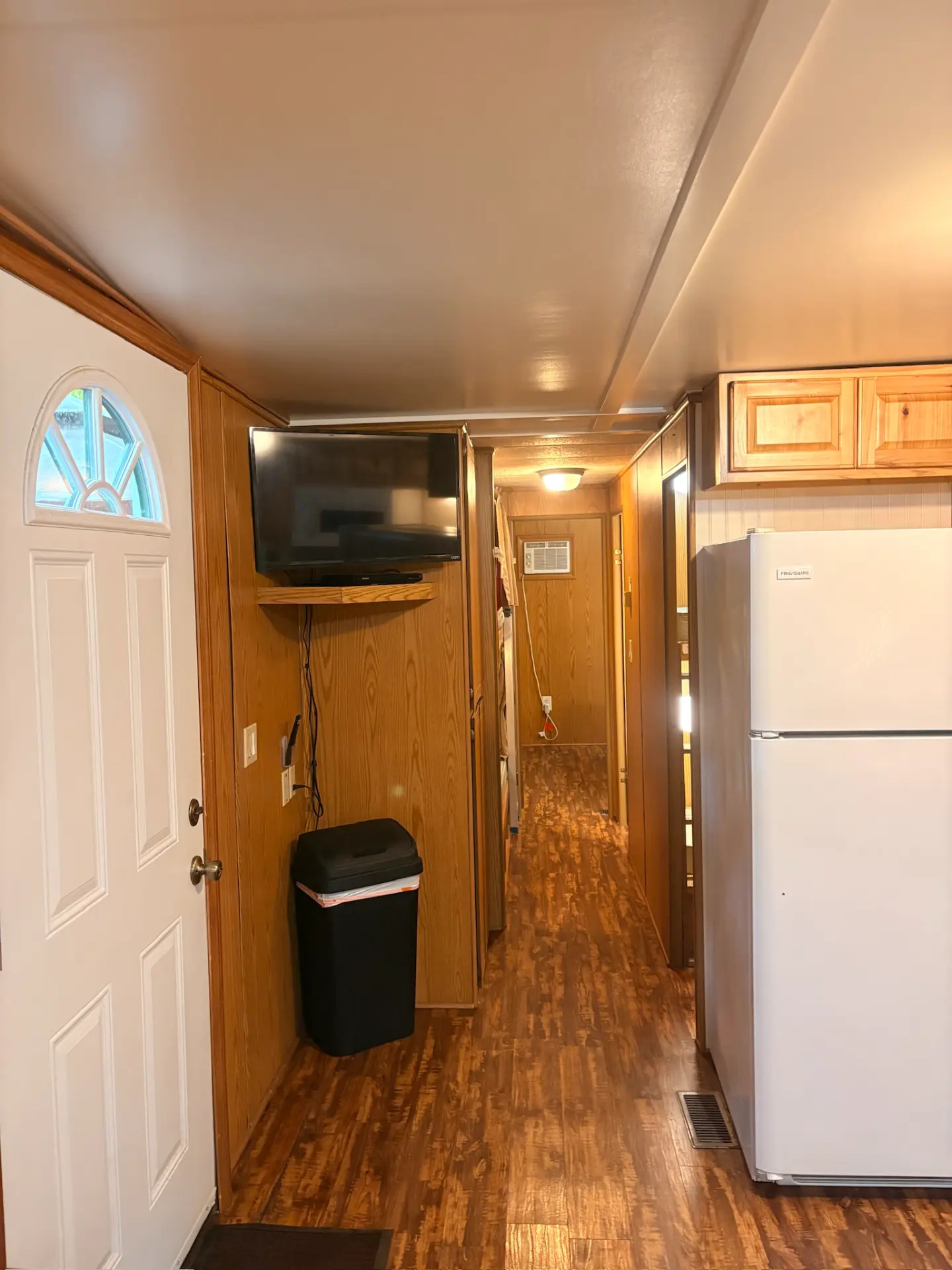 West Oak Lane 10 — Entry and hallway with a wall-mounted TV, wooden doors and the refrigerator by the kitchen
