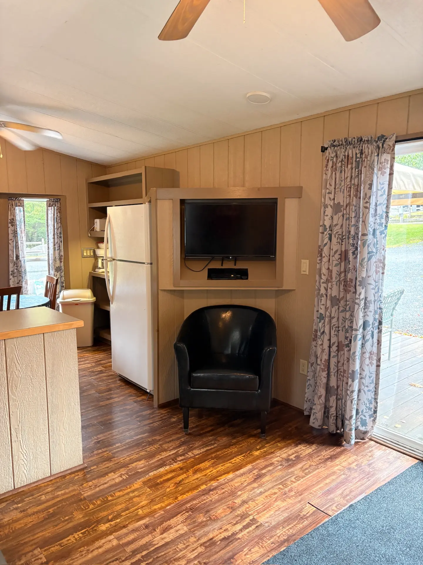 East Oak Lane 6 — TV corner with a black leather armchair, angled wood entertainment alcove and a sliding glass door out to the deck